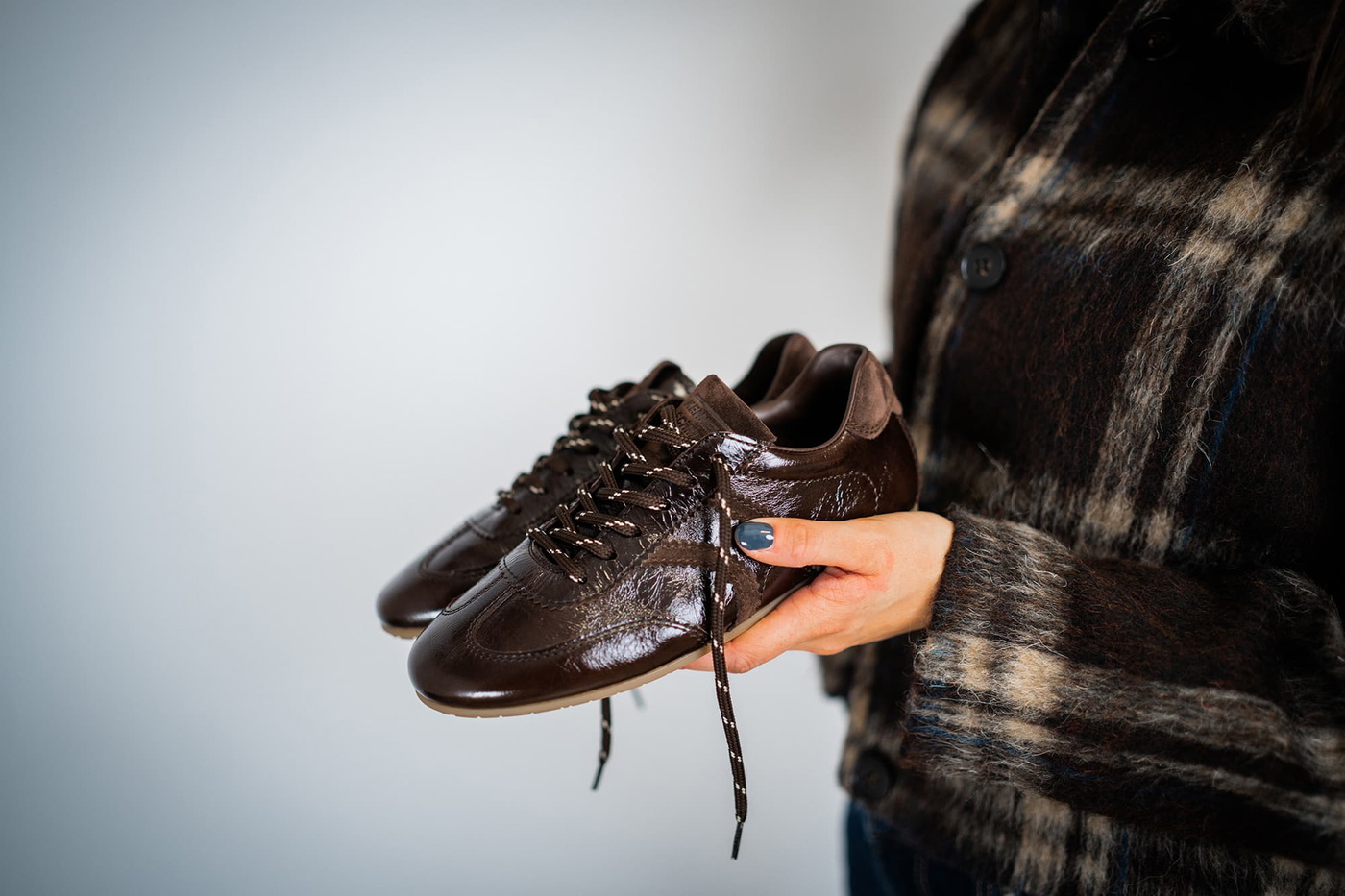 Sneaker aus glänzendem Leder in der Hand