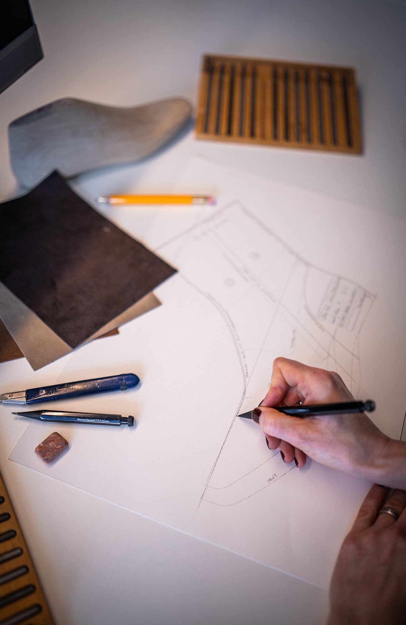 Main dessinant une esquisse de chaussure sur papier