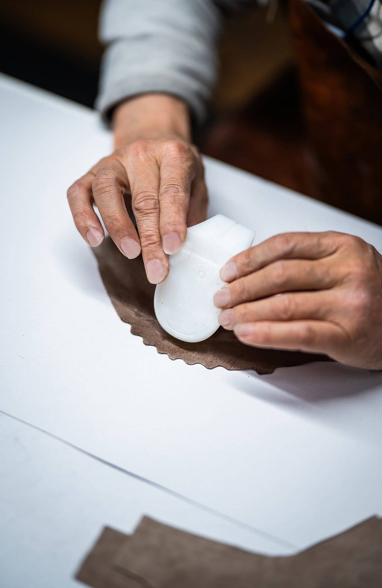 Mains façonnant un composant de semelle sur du cuir